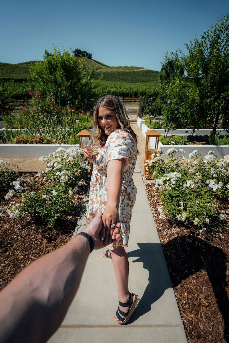 A woman holding a mans hand leading him forward for couple poses