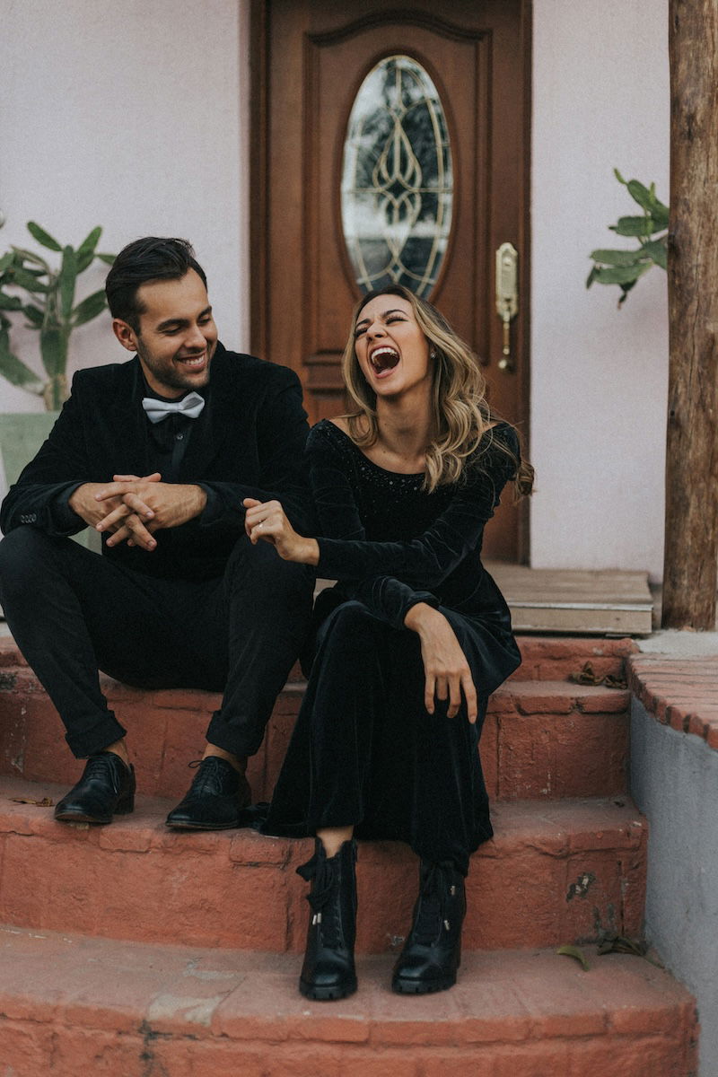 Two people sitting on steps with the woman laughing for couple poses