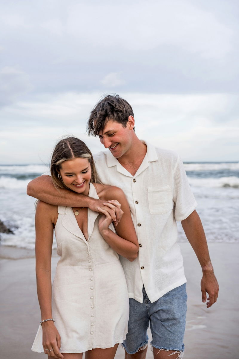 Holding hands while walking on a beach for couple poses