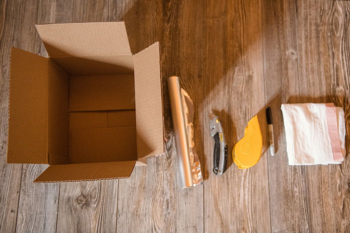 a cardboard box, aluminum foil, cutting knife, tape, stationary for making a DIY softbox