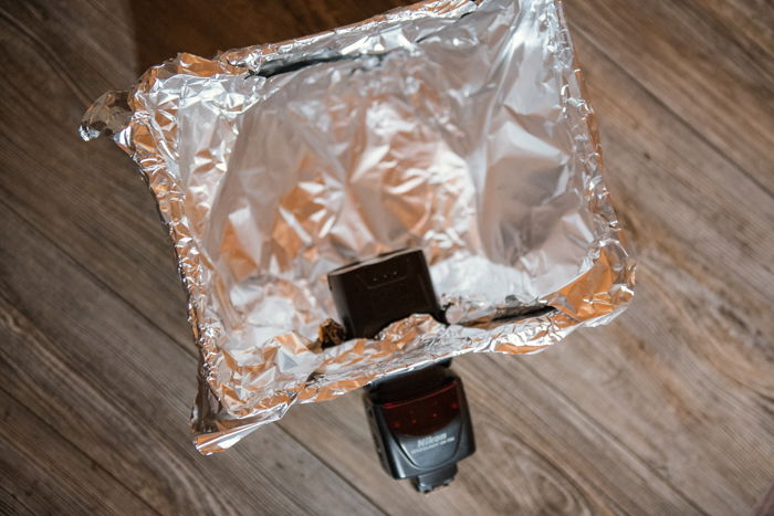 A camera flash inserted into a flap of a foil covered cardboard box