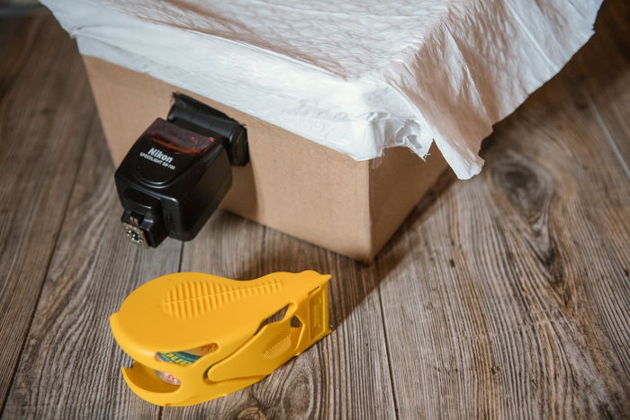 A camera flash inserted into a flap of a cardboard box