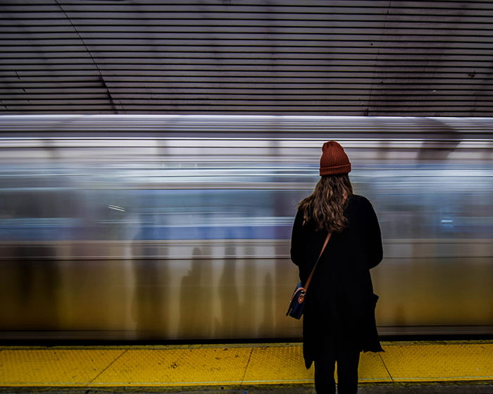 A woman stands in front of a moving train