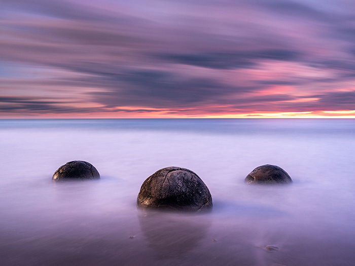 A long-exposure seascape at dusk with purple tones and milky water using filters for landscape photography