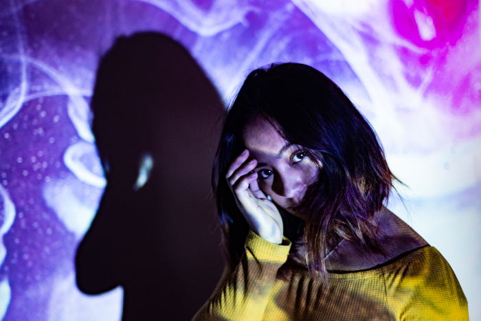 A portrait of a female model with a projected photo of colorful smoke on her