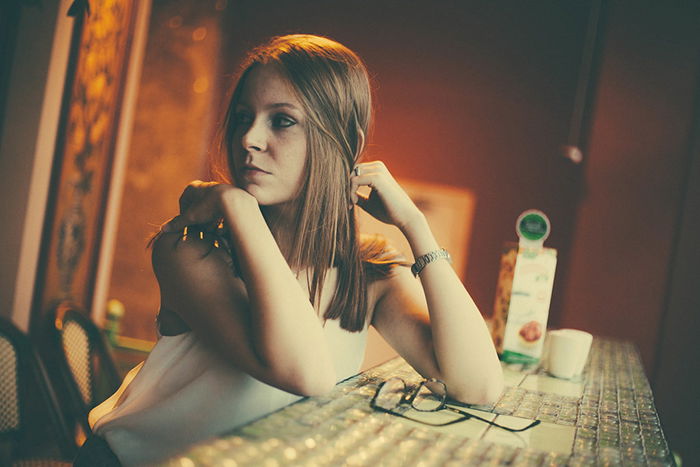 Portrait photo of a girl sitting at a table in tungsten light