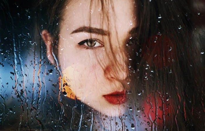 double exposure of a woman behind a wet window