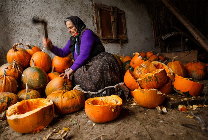 Screenshot image of a woman hacking up pumpkins outdoors from Photzy's 'Powerful Imagery' eBook 