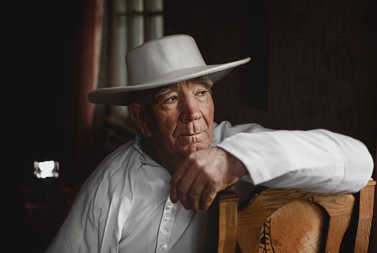 Sharp focus portrait of an old man in a shite shirt and hat