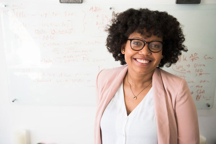 A commercial headshot of a woman in glasses with curly hair