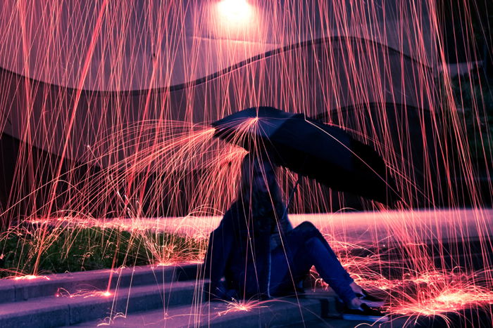 a girl holding an umbrella under the rain effect created by steel wool photography