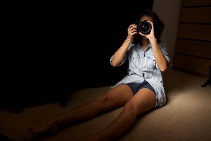 A girl on a bed taking a photograph