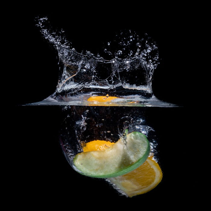 A slice of fruit photographed as it drops into water and creates a splash