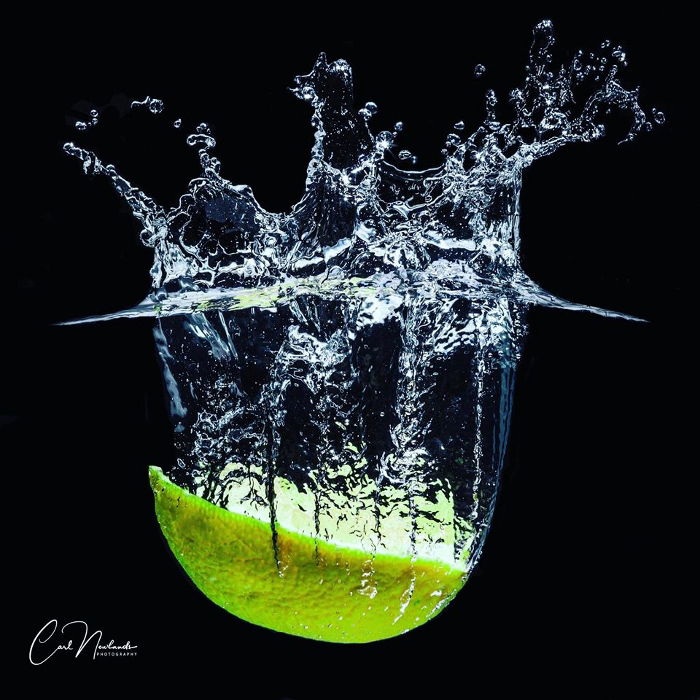 A slice of fruit photographed as it drops into water and creates a splash