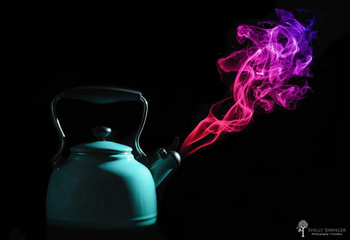 A tea pot with purple smoke coming out of it