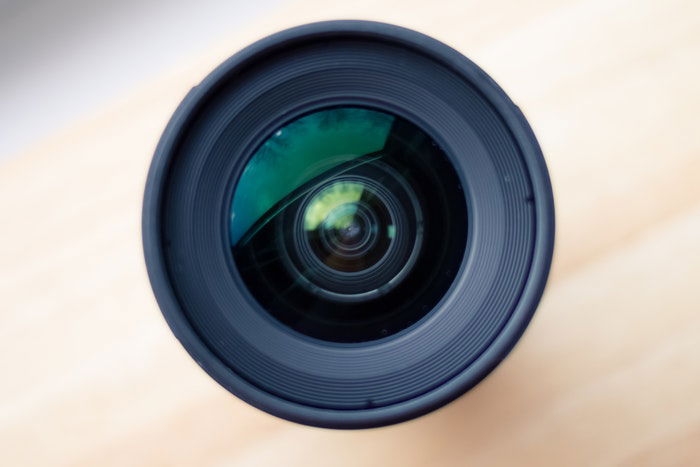 Black camera lens with shutter on wooden surface