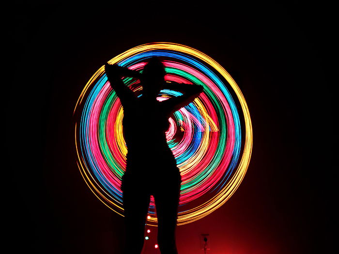 Colorful light graffiti behind the silhouette of a woman.