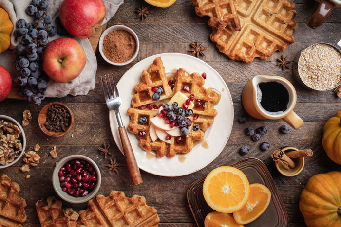 Overhead shot of waffles and fruit on a rustic table