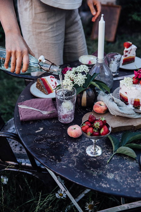 A person pouring a drink on an outdoor picnic table