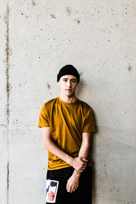 A young man posing in front of a wall