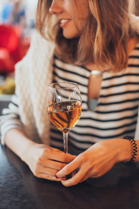 A girl holding a glass of white wine