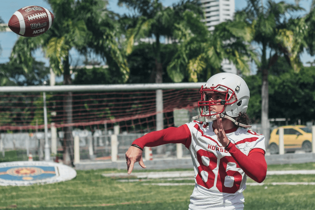 A football player in a helmet and jersey through a football for high-speed photography