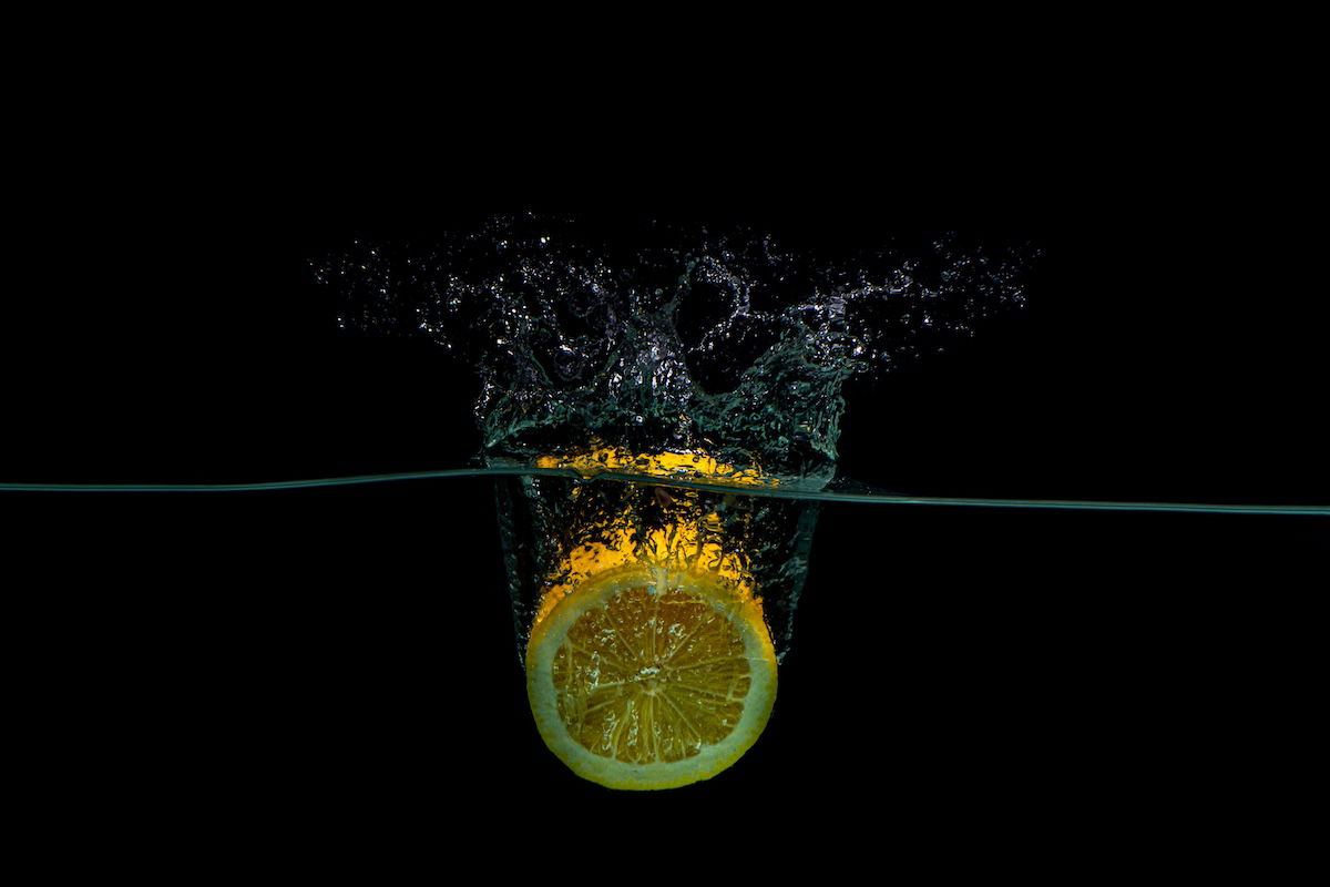 A lemon dropped in water creating a splash for high-speed photography