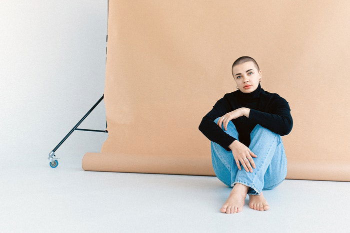 Woman sitting in front of a pink backdrop in a home photo studio 