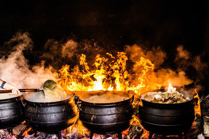 Scene of Indian food being cooked in pots over an open fire