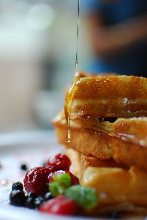 Closeup of syrup being drizzled onto a stack of pancakes