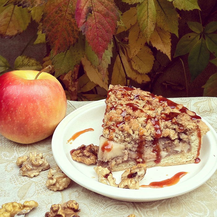 A close up of a slice of apple pie beside an apple