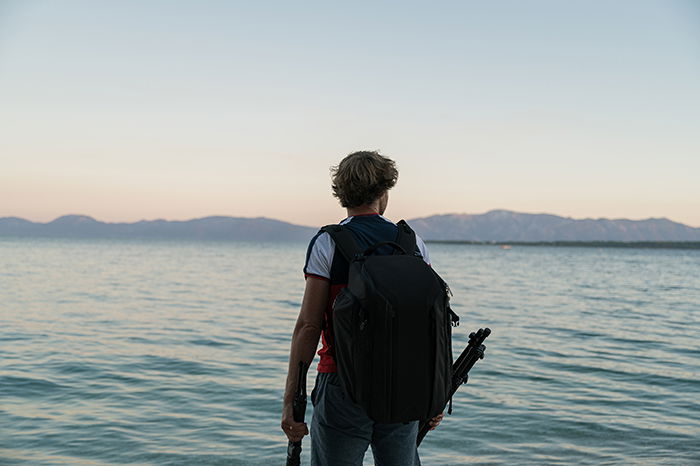 Male photographer with tripod in his hands during blue hour.