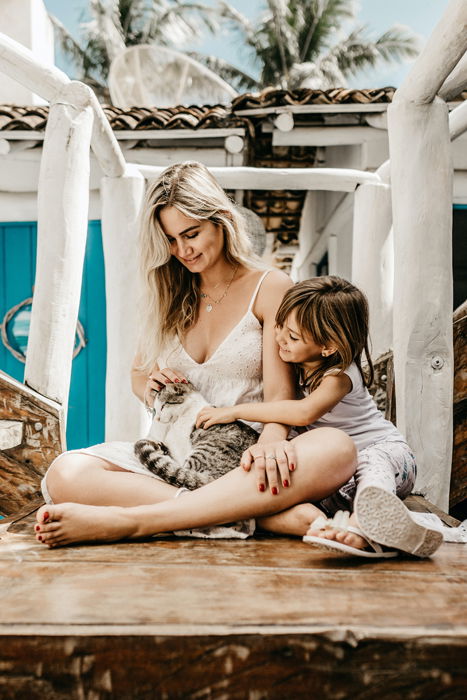 Mother and daughter petting their cat as an example of family photos with pets