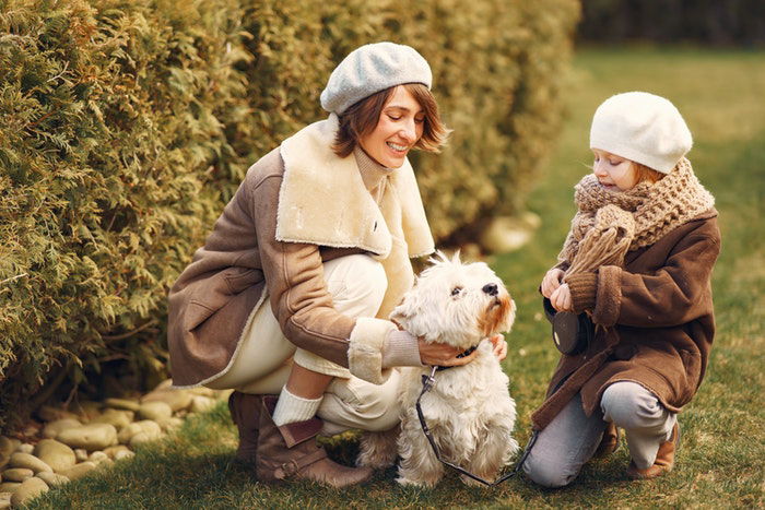 Mother and daughter petting their dog outdoors as an example of family photos with pets