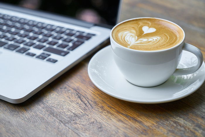 A cup of coffee beside a laptop