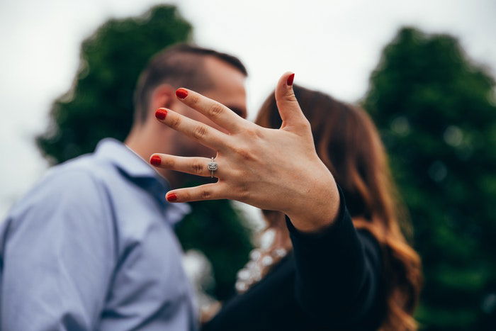 A couple facing each other with the womans hand blocking the cameras view