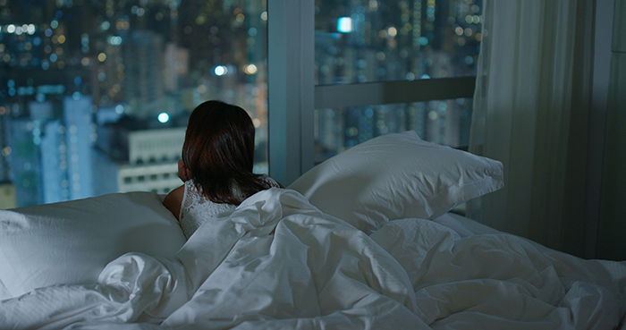 Woman looking at the city from window at night.