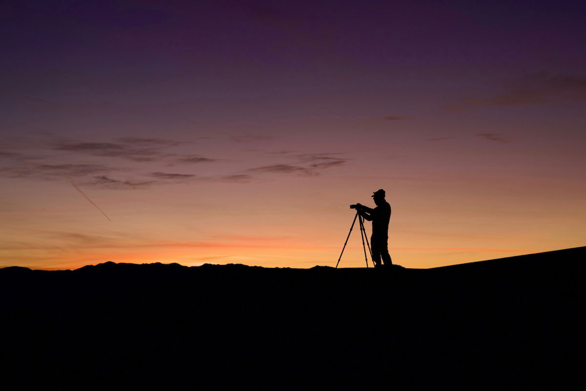 Silhouette of a photographer and tripod on a ridge at sunrise for a photography challenge