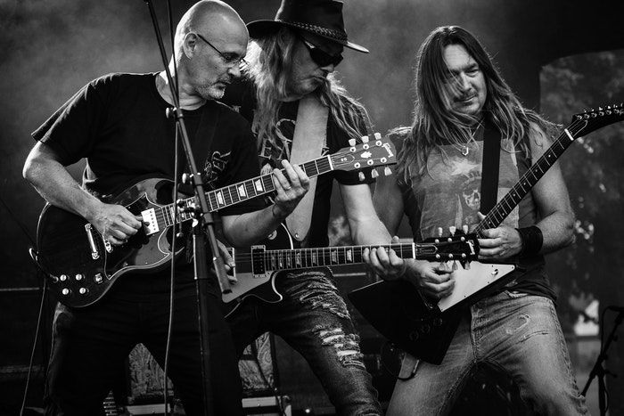 A close up of three guitarists onstage during a live gig