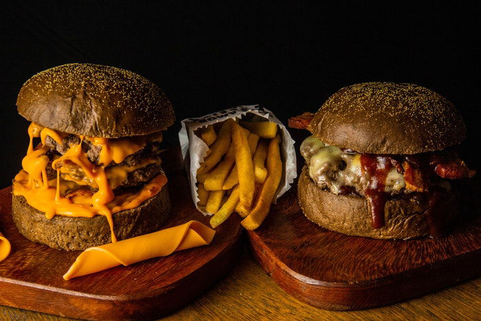 Eye-level photo of two burgers with fries in between