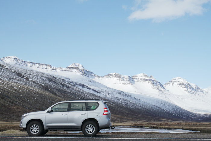 Photo of a silver car with mountains in the background