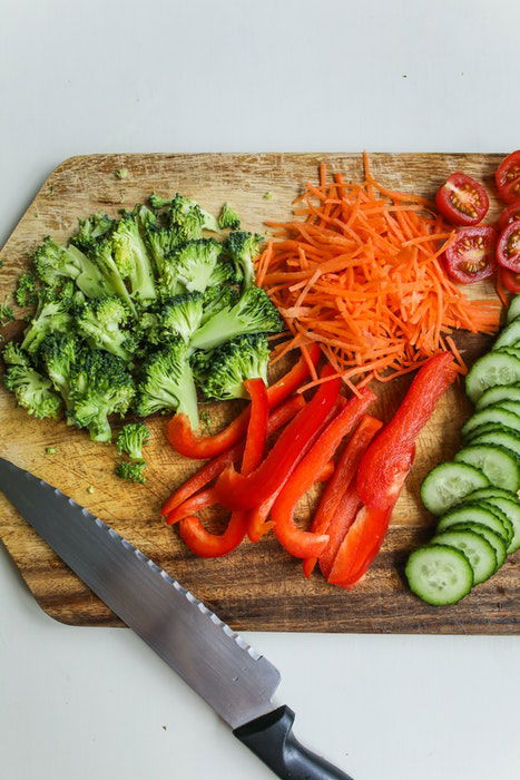 Overhead shot of cutting fruit and vegetables on a wooden chopping board