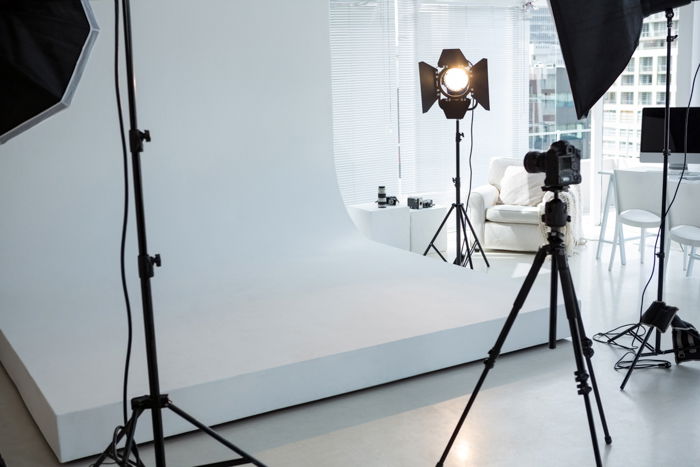 Empty photo studio with tripod, lighting equipment and digital camera