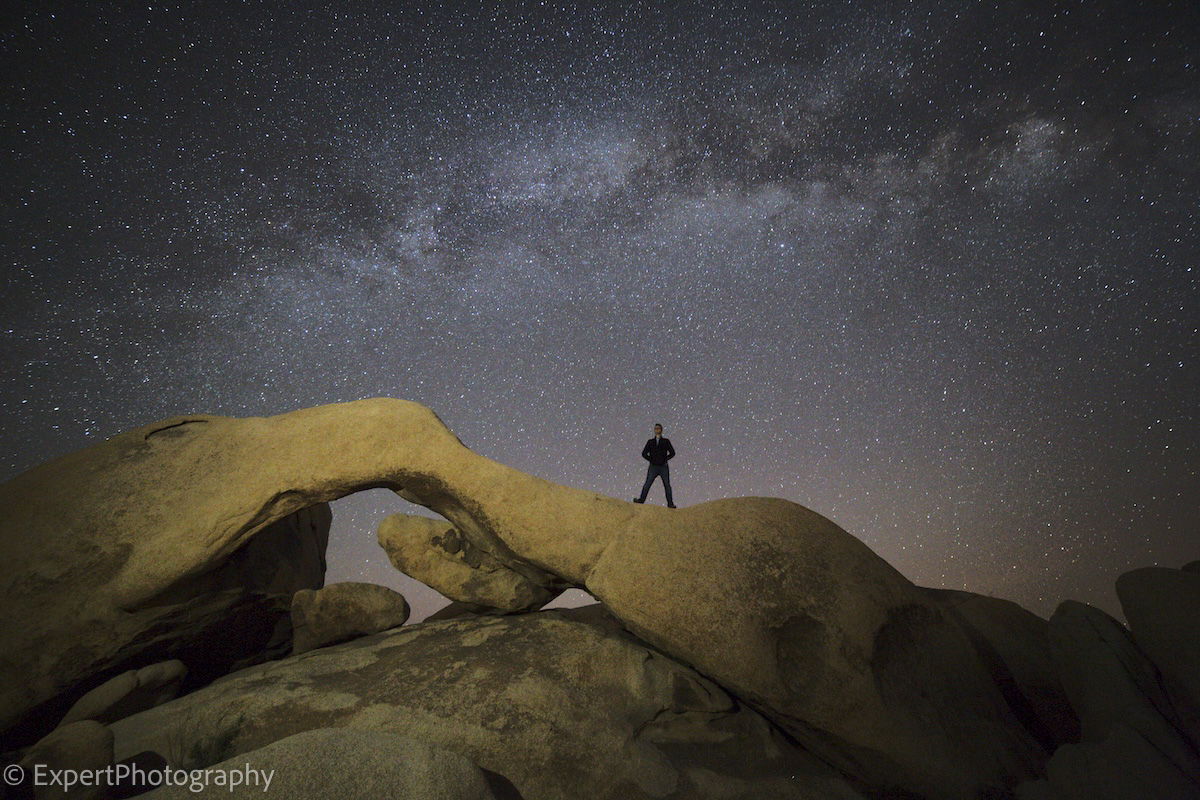 An environmental starry-night sky portrait with an ExpertPhotography text watermark for copyright