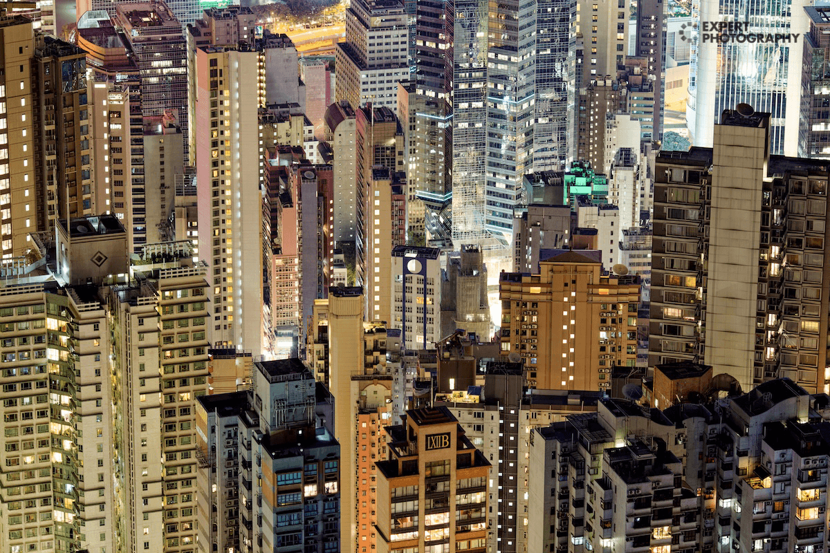 An urban landscape of buildings at night with an ExpertPhotography watermark