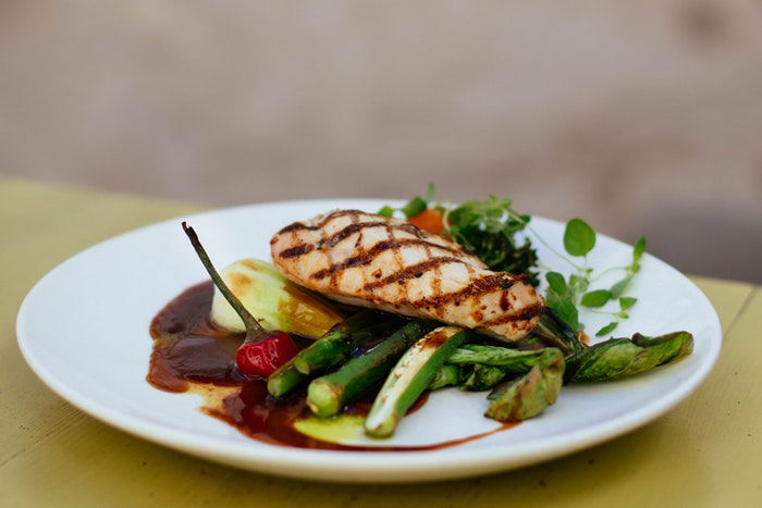 A plate of chicken breast served on vegetables