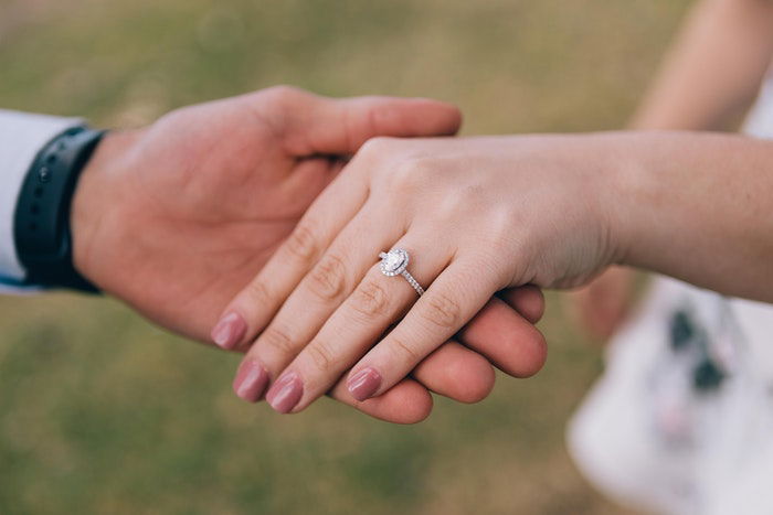 A wedding portrait closeup of the newlyweds holding hands outdoors