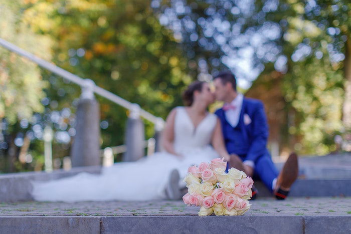 Blurry wedding portrait of the newlyweds kissing outdoors