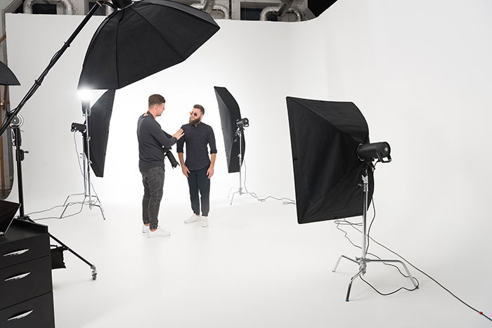 Two men standing in a photo studio with strobe lights.