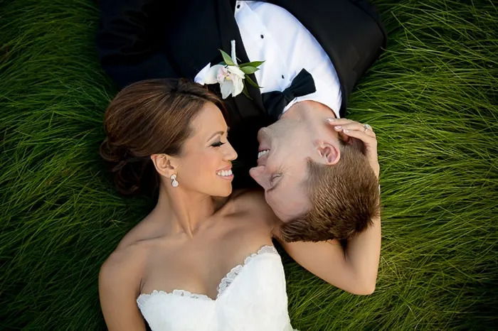 Wedding portrait of the newlywed couple lying on the grass